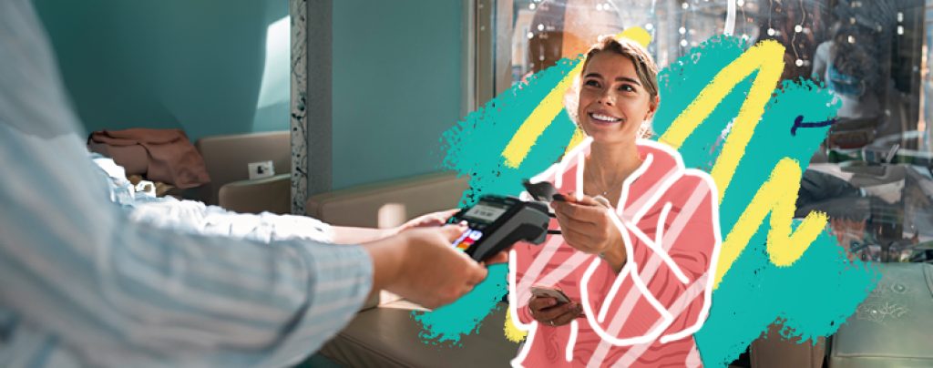 Smiling woman at a coffee shop paying with a credit card.